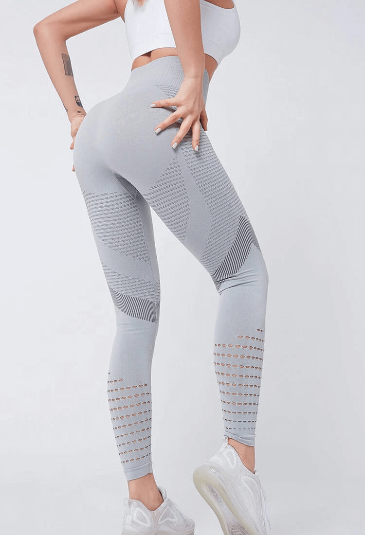 Woman wearing grey seamless high-waisted leggings, featuring hollow design and booty-lifting fit, ideal for fitness and exercise.